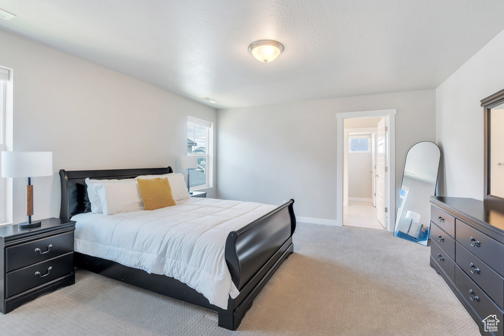 Bedroom featuring light carpet, baseboards, and ensuite bath