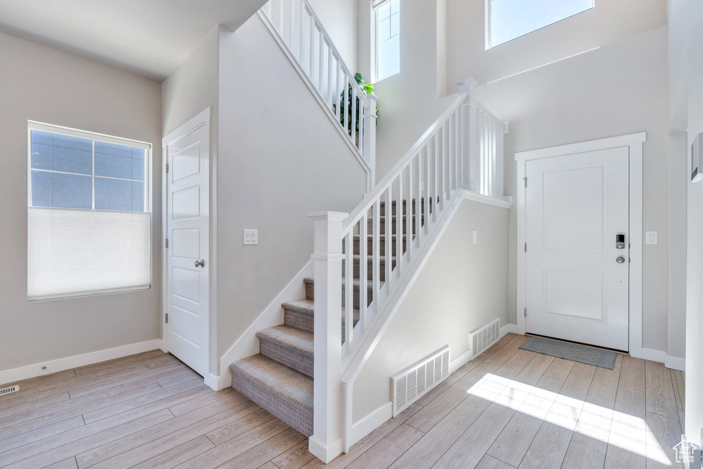 Foyer featuring stairway, wood finished floors, baseboards, and a high ceiling