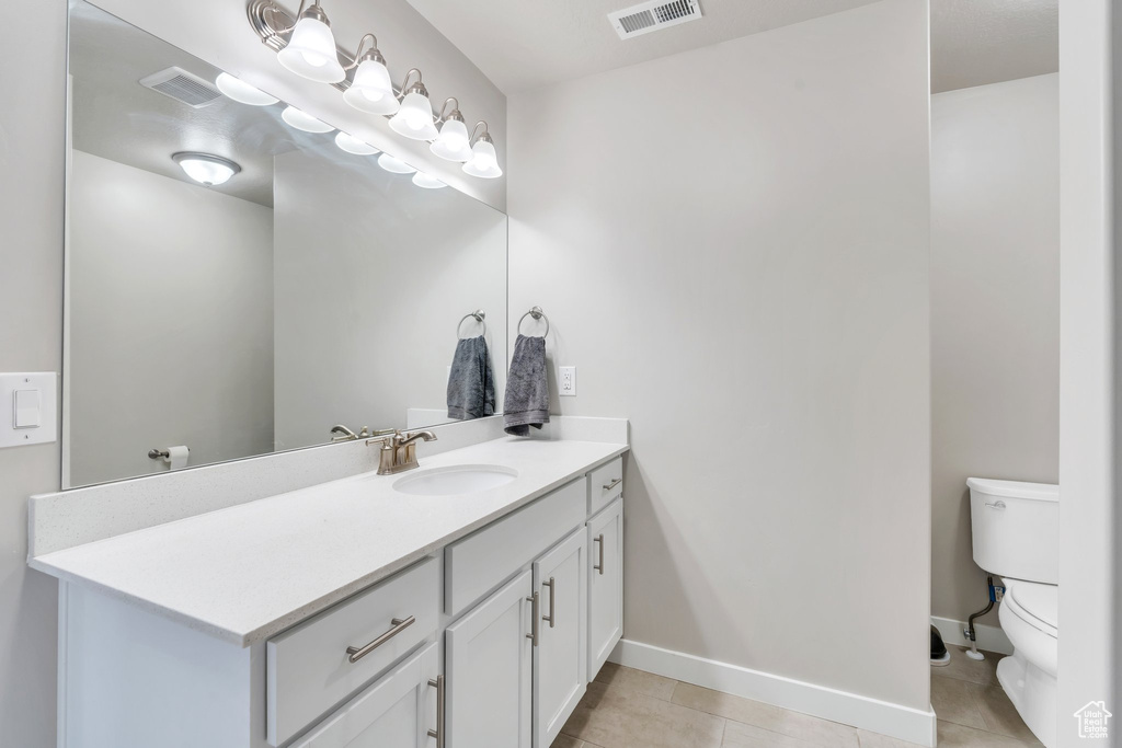 Bathroom with toilet, tile patterned floors, vanity, and baseboards