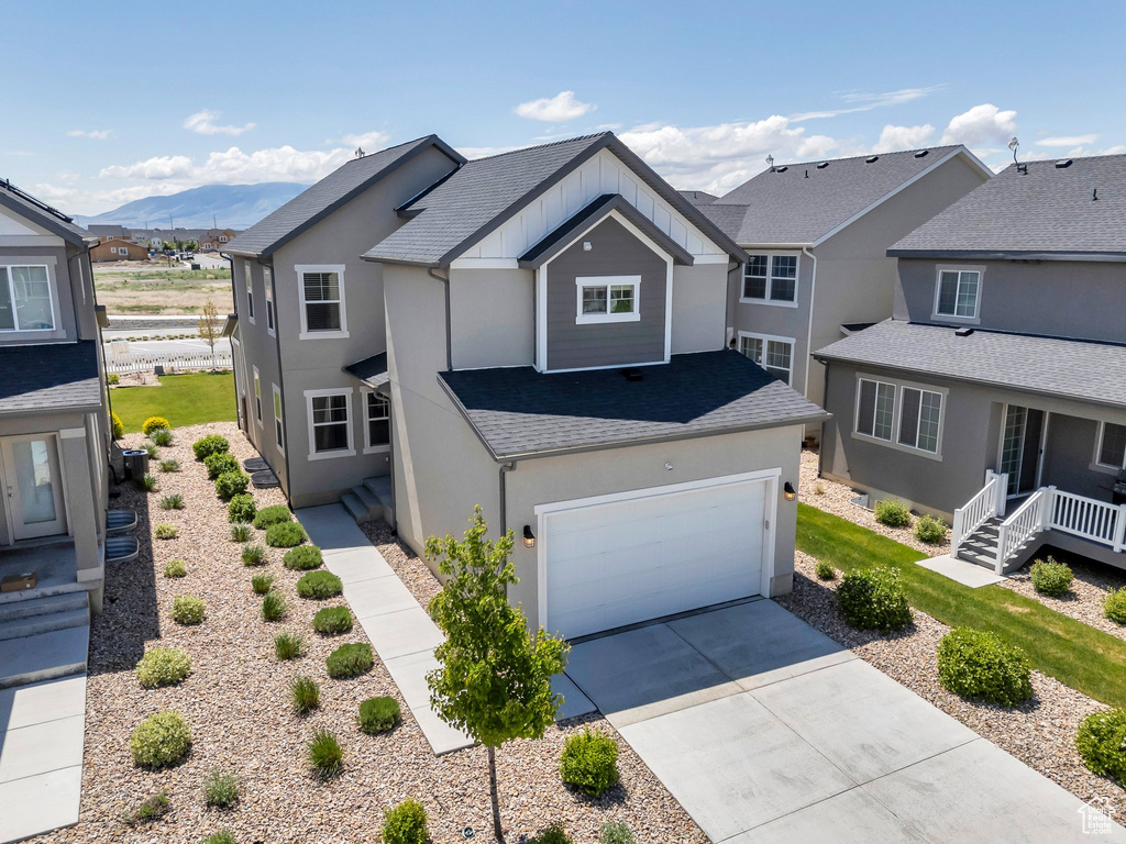 Traditional home with stucco siding, concrete driveway, a mountain view, and roof with shingles