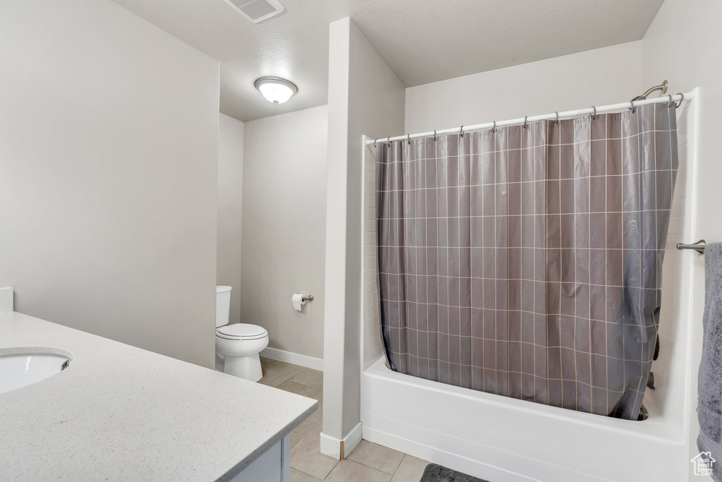 Bathroom with toilet, vanity, tile patterned floors, and shower / tub combo with curtain