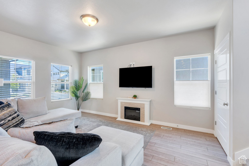 Living area featuring light wood finished floors, baseboards, and a glass covered fireplace