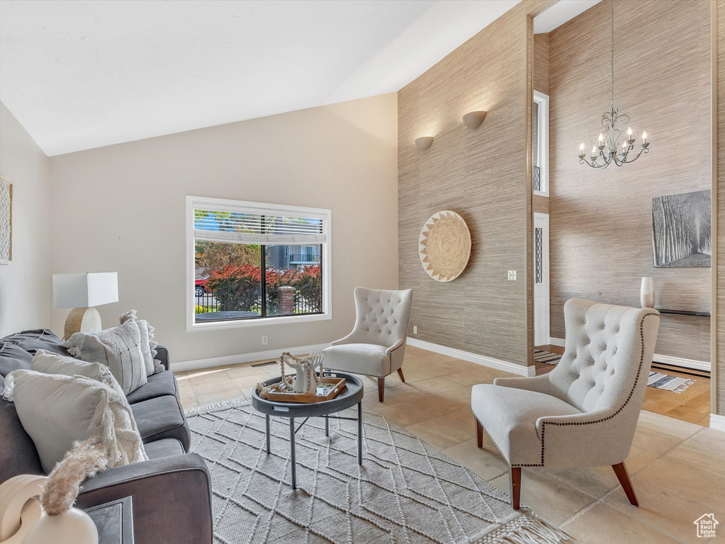 Living room with a chandelier, light tile patterned floors, baseboards, and high vaulted ceiling