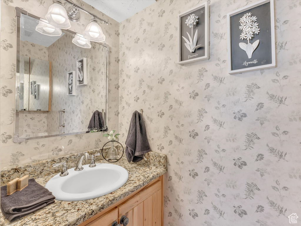 Bathroom with vanity and wallpapered walls
