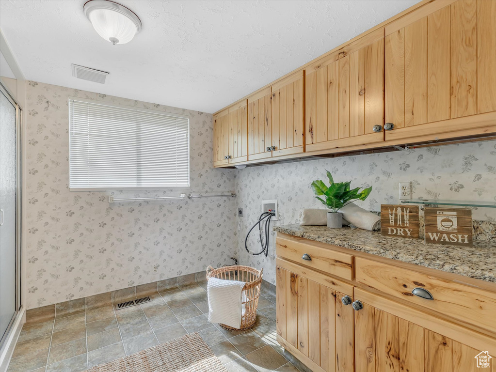 Laundry room with hookup for a washing machine, cabinet space, wallpapered walls, and baseboards