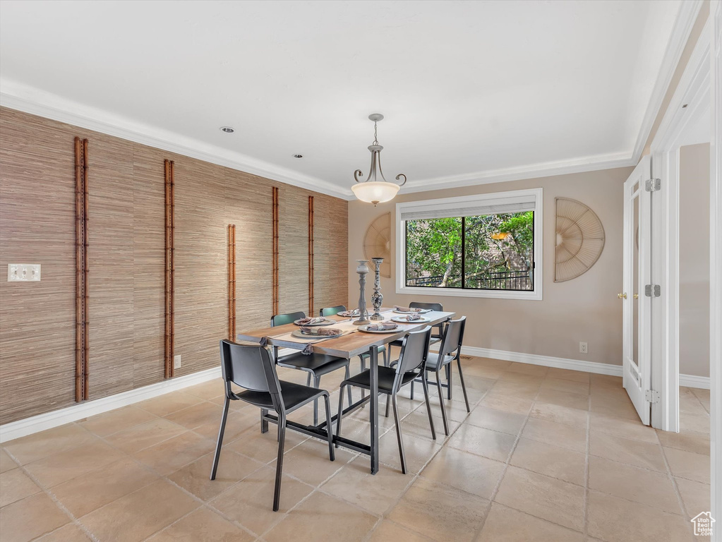 Dining area with baseboards, light tile patterned flooring, and crown molding