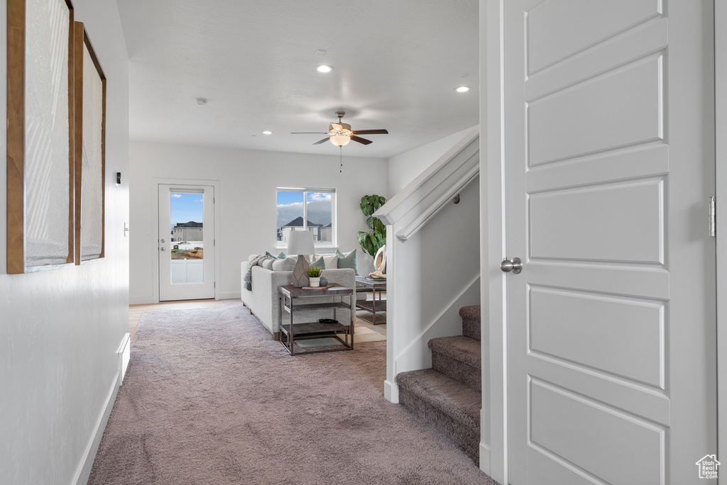 Carpeted living room featuring a ceiling fan, baseboards, recessed lighting, and stairs