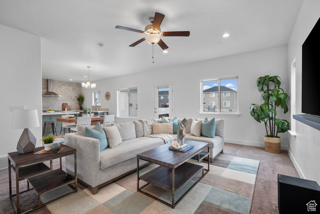 Living room featuring a chandelier, a ceiling fan, recessed lighting, light colored carpet, and baseboards