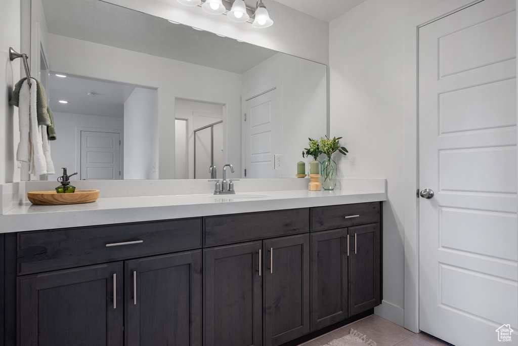Full bathroom featuring vanity, a stall shower, tile patterned flooring, and baseboards