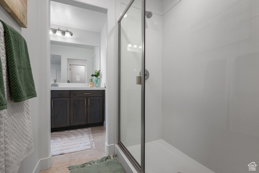 Bathroom with a shower stall, vanity, and tile patterned flooring