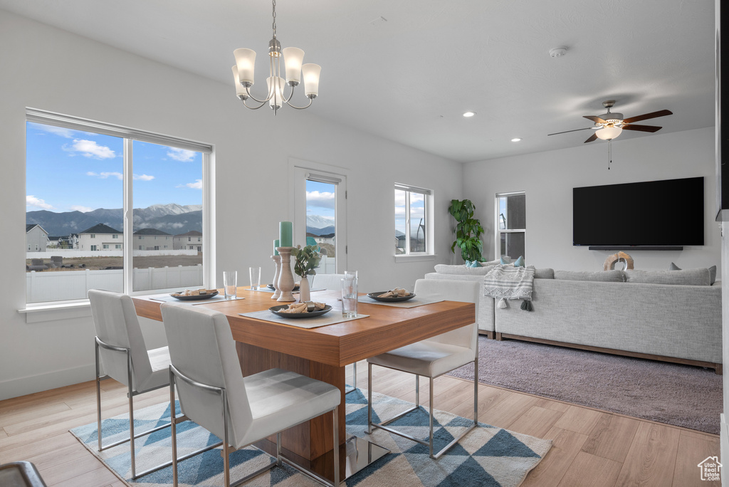 Dining room with a mountain view, a chandelier, recessed lighting, light wood-type flooring, and a ceiling fan