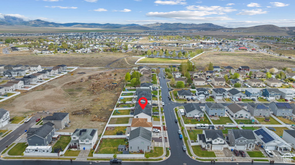Aerial view of property and surrounding area featuring mountains and nearby suburban area