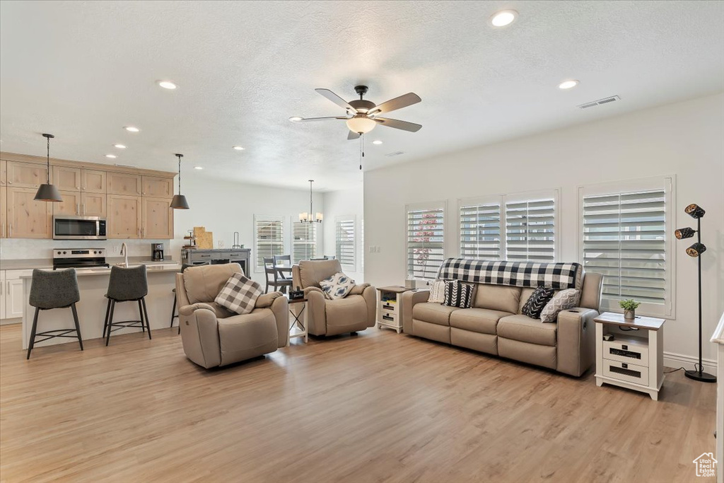 Living room with ceiling fan, light wood-type flooring, recessed lighting, and a chandelier
