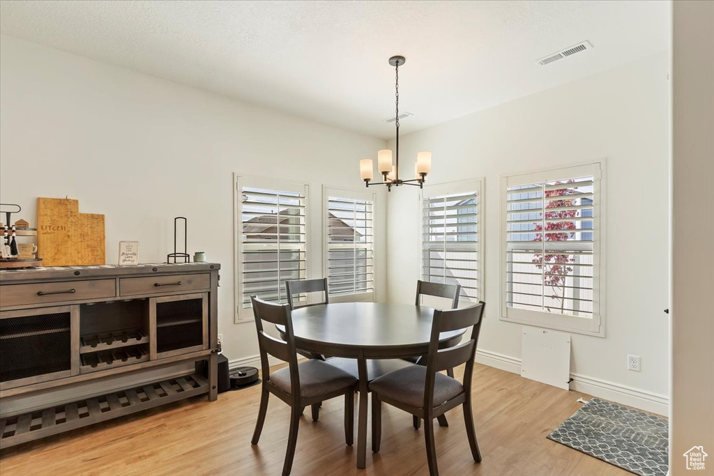 Dining room featuring a chandelier, light wood finished floors, plenty of natural light, and baseboards