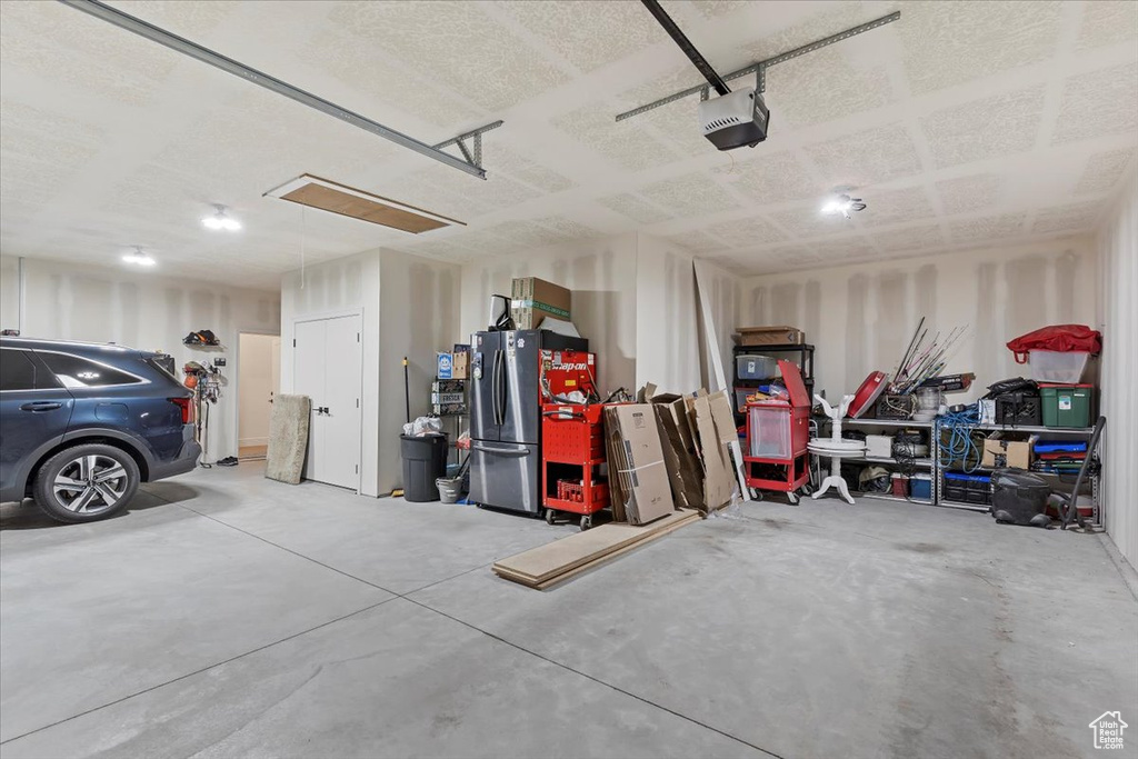 Garage with freestanding refrigerator and a garage door opener