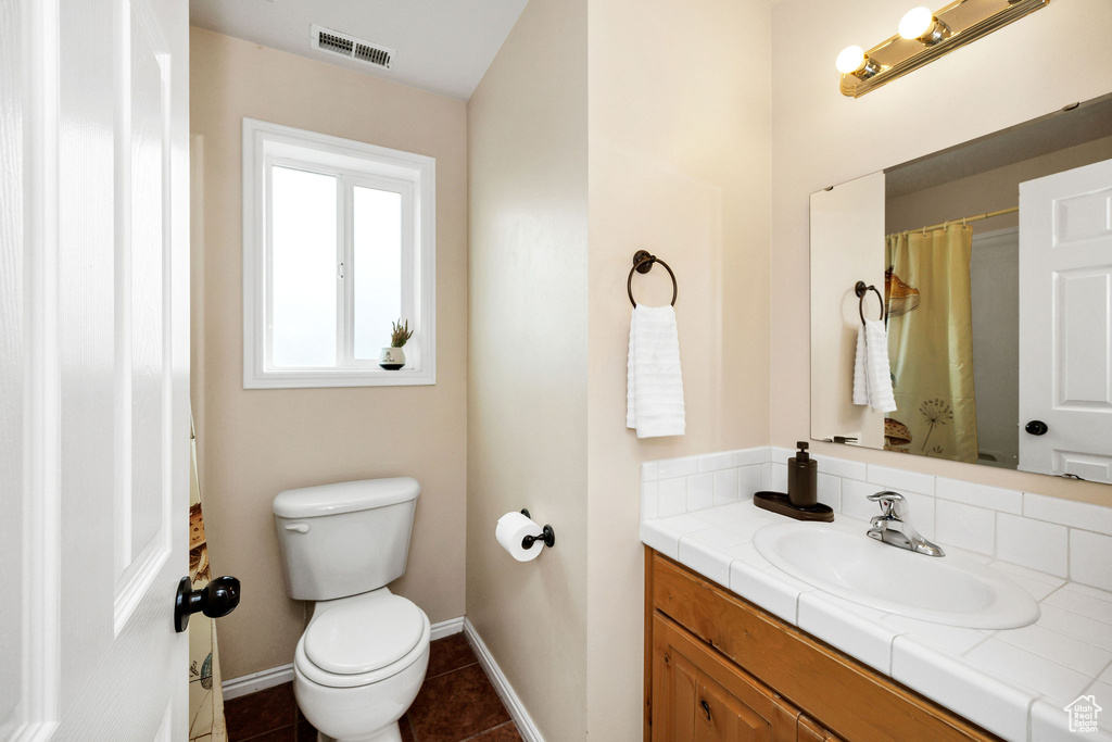 Bathroom featuring toilet, baseboards, tile patterned floors, and vanity