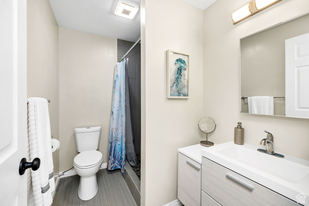 Full bathroom with toilet, a shower with curtain, vanity, and baseboards