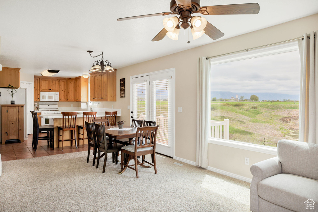 Dining room with ceiling fan, baseboards, and light carpet
