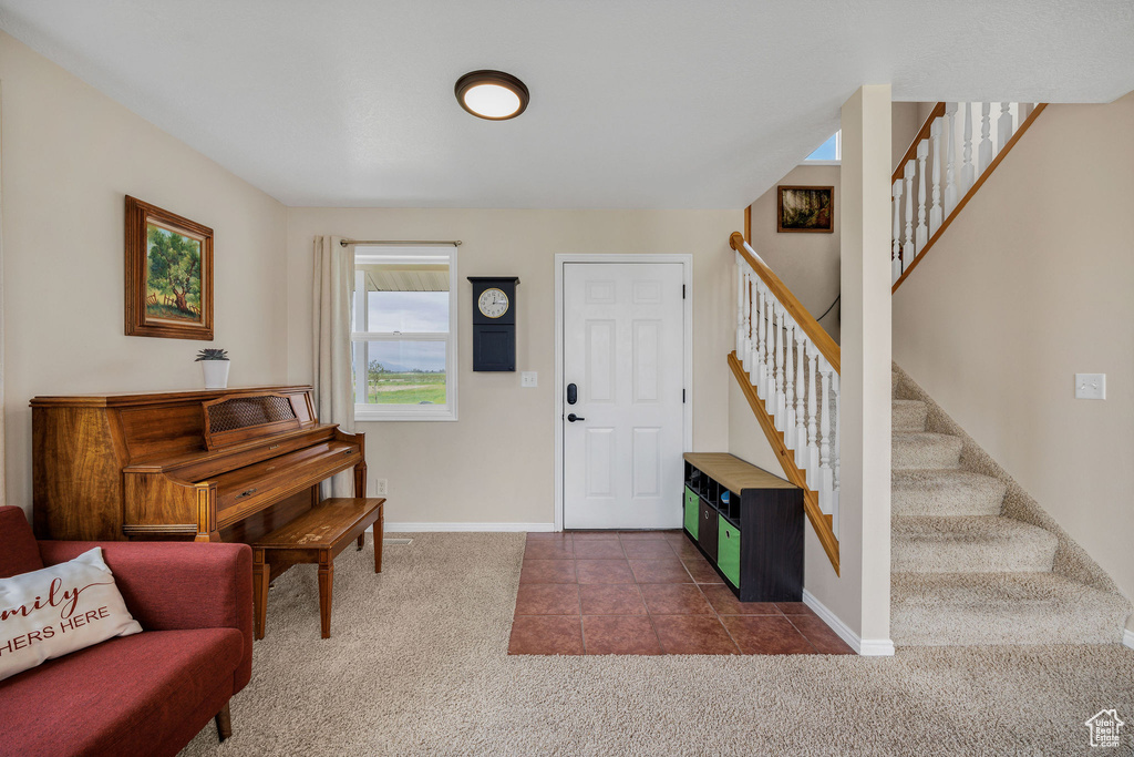 Foyer entrance featuring dark colored carpet, baseboards, stairway, and dark tile patterned floors