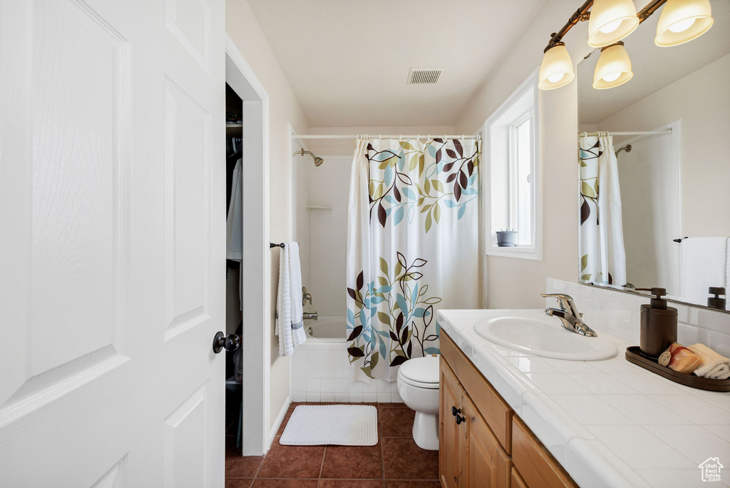 Bathroom with vanity, shower / tub combo, tile patterned flooring, and toilet