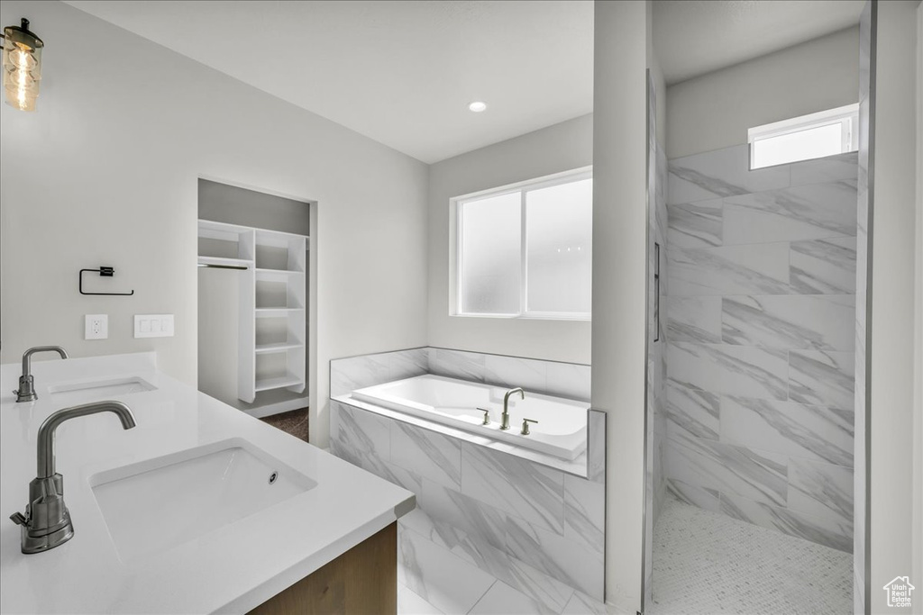 Bathroom with double vanity, a garden tub, plenty of natural light, and recessed lighting