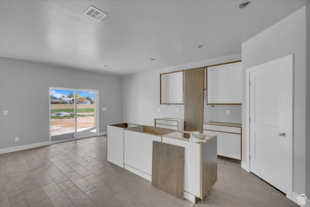 Kitchen with white cabinets, baseboards, a center island, and light wood-style floors