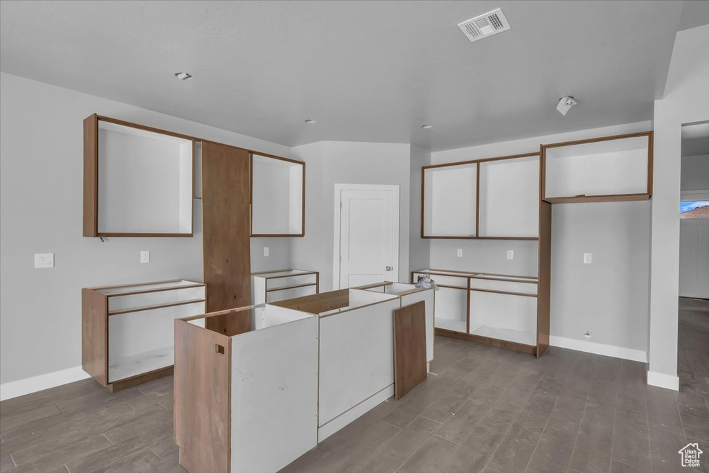Kitchen featuring wood finished floors, a kitchen island, white cabinets, and baseboards
