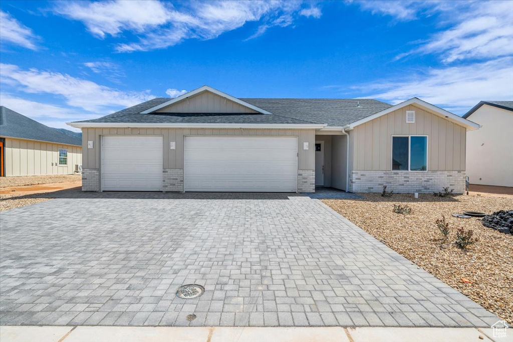 Ranch-style home with brick siding, decorative driveway, a garage, and a shingled roof