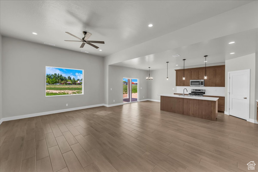 Unfurnished living room with a sink, wood finished floors, ceiling fan, recessed lighting, and baseboards
