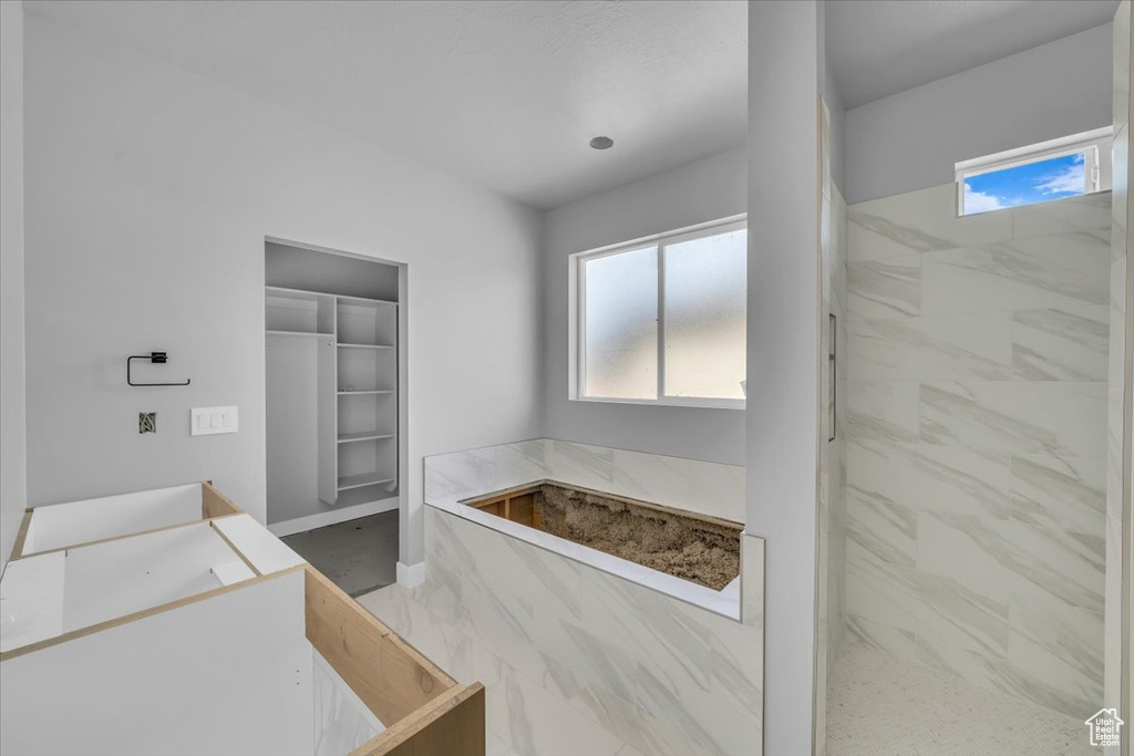 Bathroom with healthy amount of natural light, a shower, and baseboards