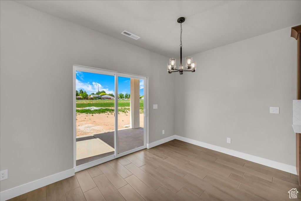 Spare room featuring a chandelier, baseboards, and wood finished floors