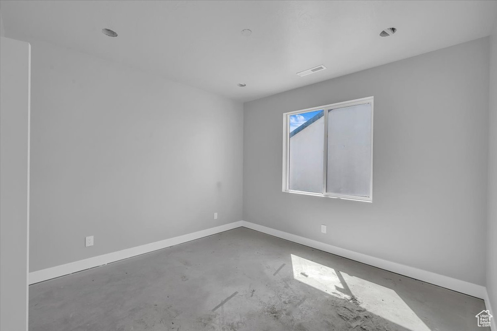 Empty room with unfinished concrete floors and baseboards