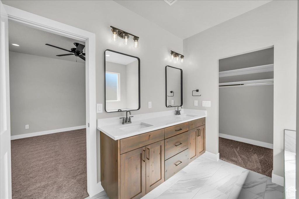 Bathroom with a ceiling fan, double vanity, baseboards, and marble finish floors
