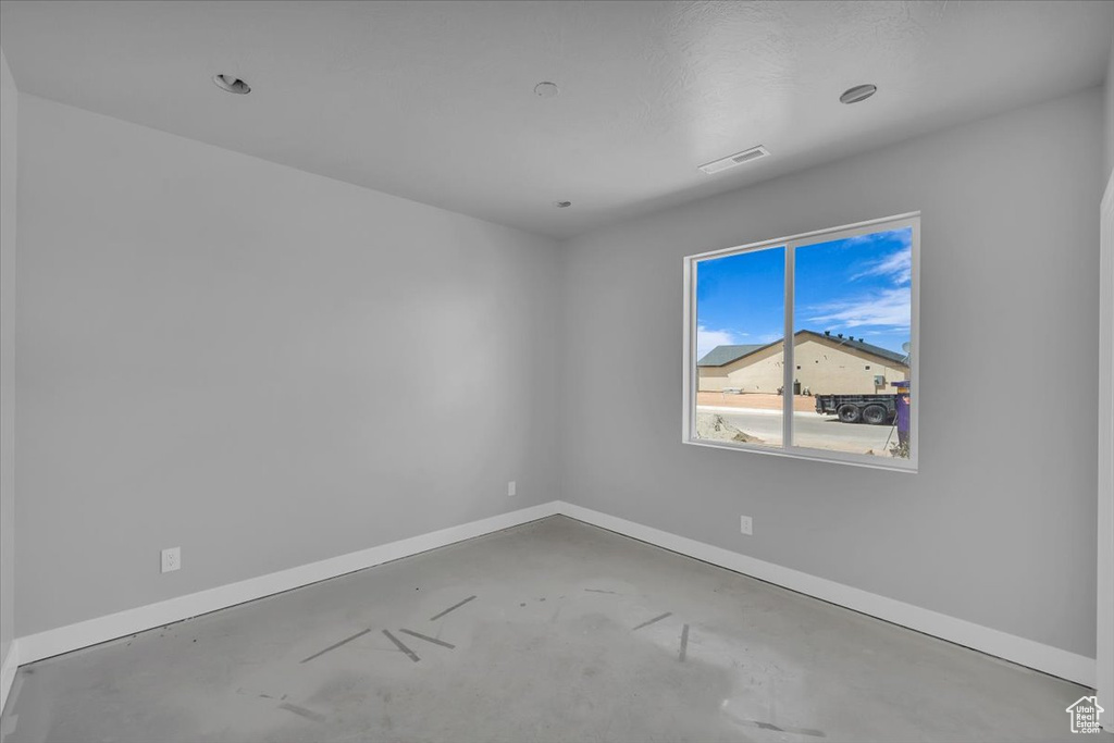 Empty room with unfinished concrete floors and baseboards