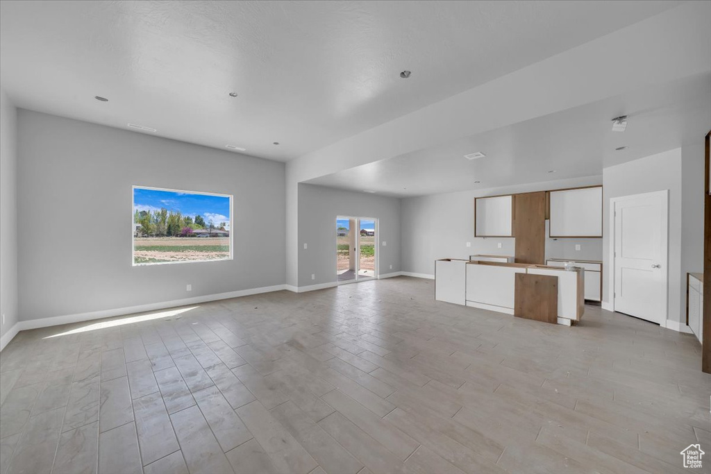 Unfurnished living room with baseboards and light wood-type flooring