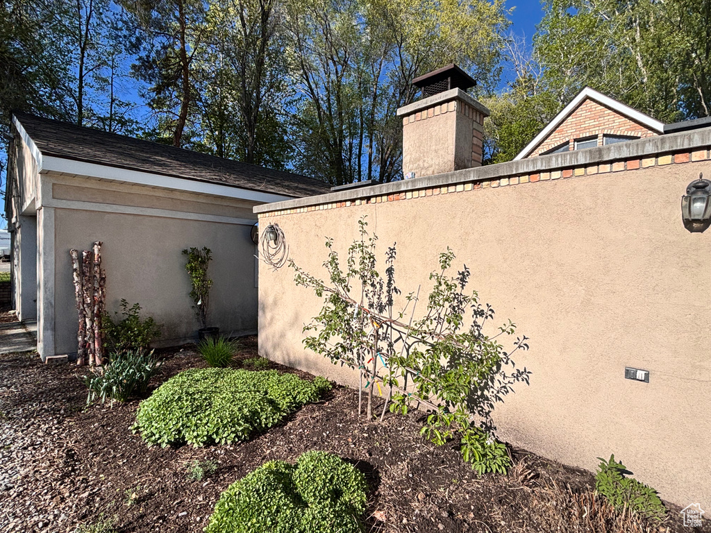 View of side of home with stucco siding and a chimney