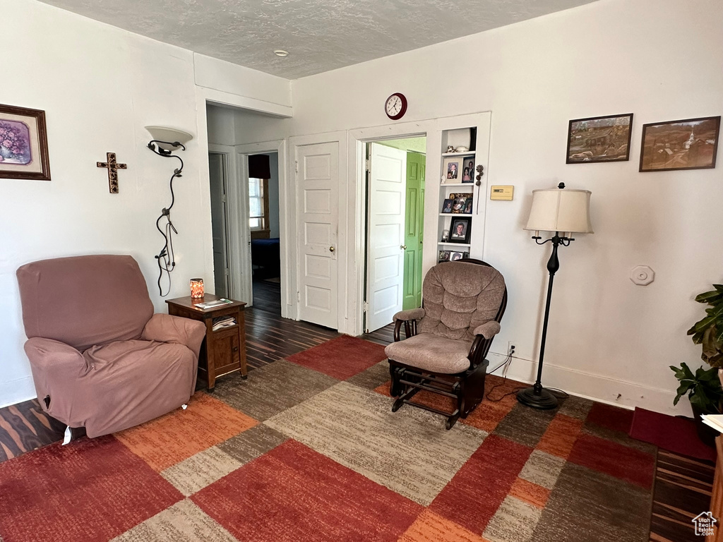 Living area with a textured ceiling, baseboards, and wood finished floors
