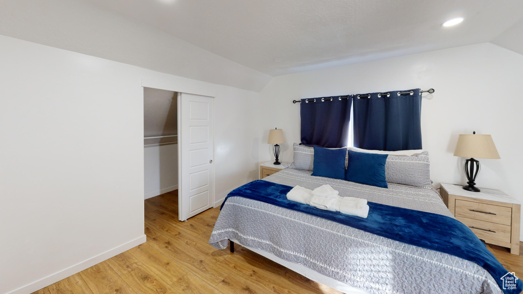 Bedroom with lofted ceiling, wood finished floors, baseboards, a closet, and recessed lighting