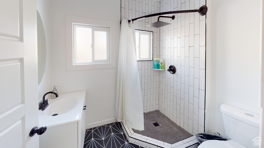 Full bathroom featuring a shower stall, toilet, vanity, tile patterned floors, and baseboards