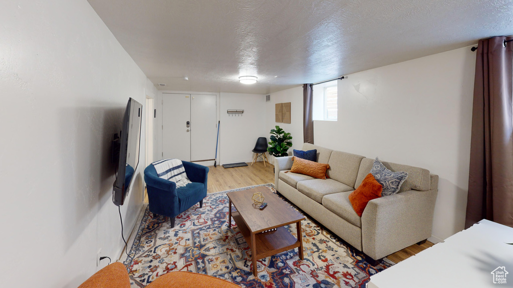 Living area featuring light wood finished floors and a textured ceiling