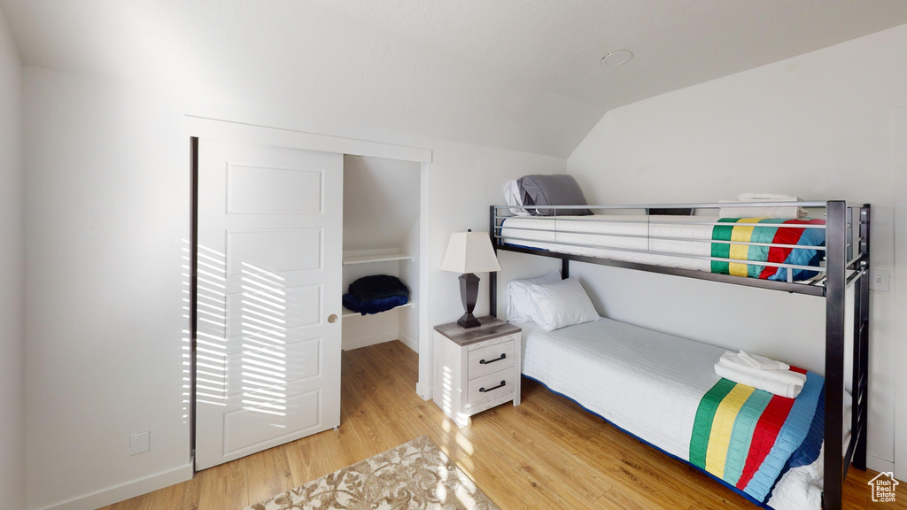 Bedroom with vaulted ceiling, light wood-type flooring, and baseboards