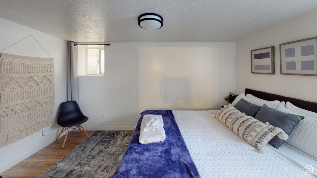 Bedroom with wood finished floors, baseboards, and a textured ceiling