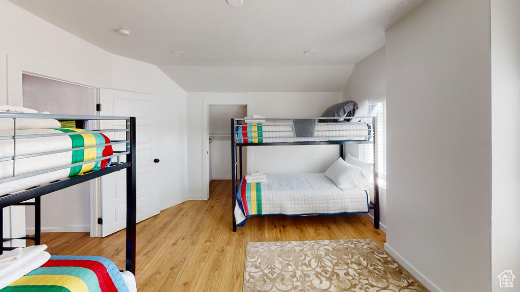 Bedroom featuring lofted ceiling, light wood-type flooring, and baseboards
