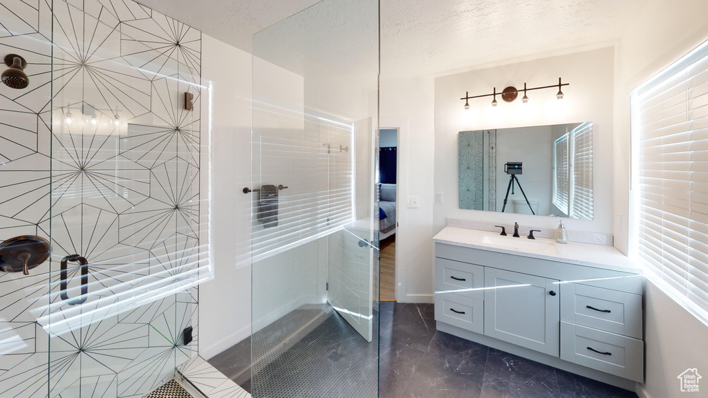 Bathroom featuring marble look tiles, a tile shower, and vanity