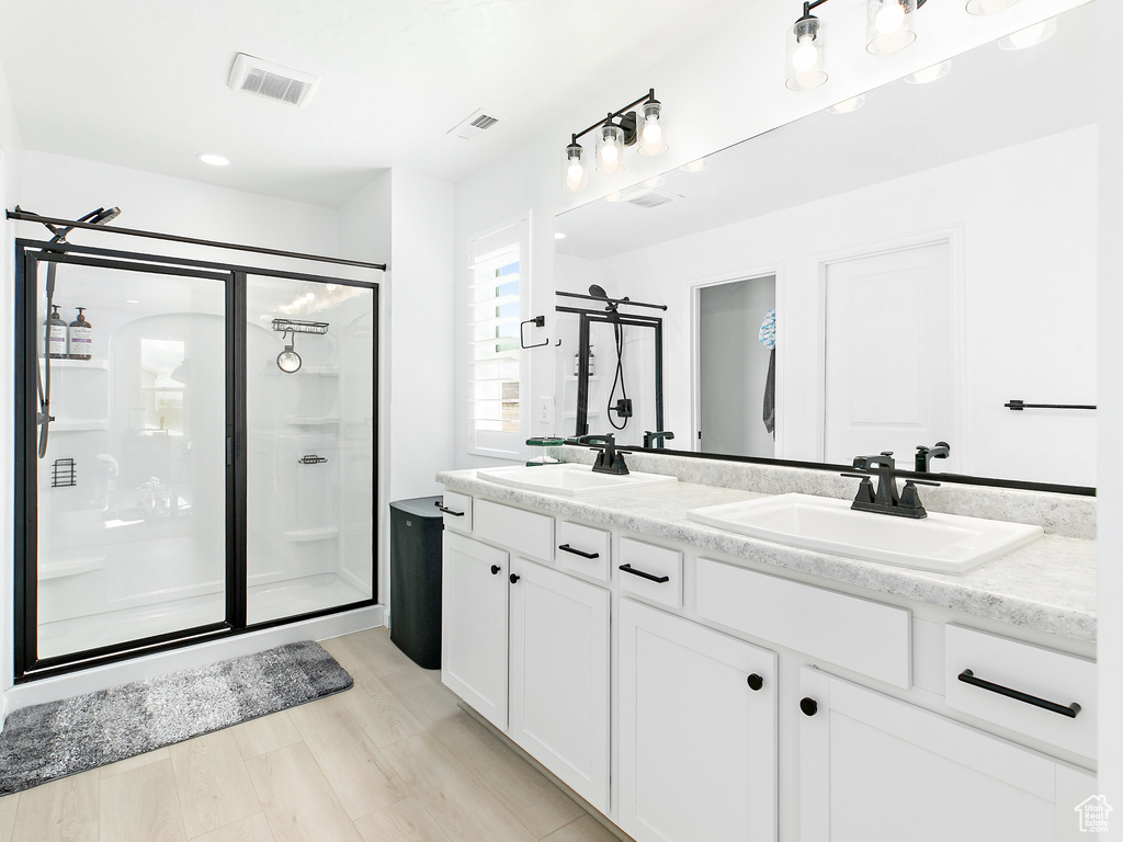 Bathroom featuring a shower stall, double vanity, and recessed lighting