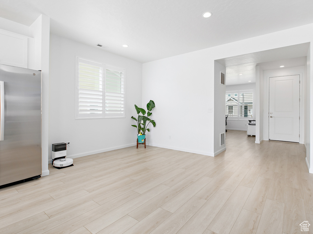 Kitchen with stainless steel fridge with ice dispenser, light wood-type flooring, white cabinets, recessed lighting, and baseboards