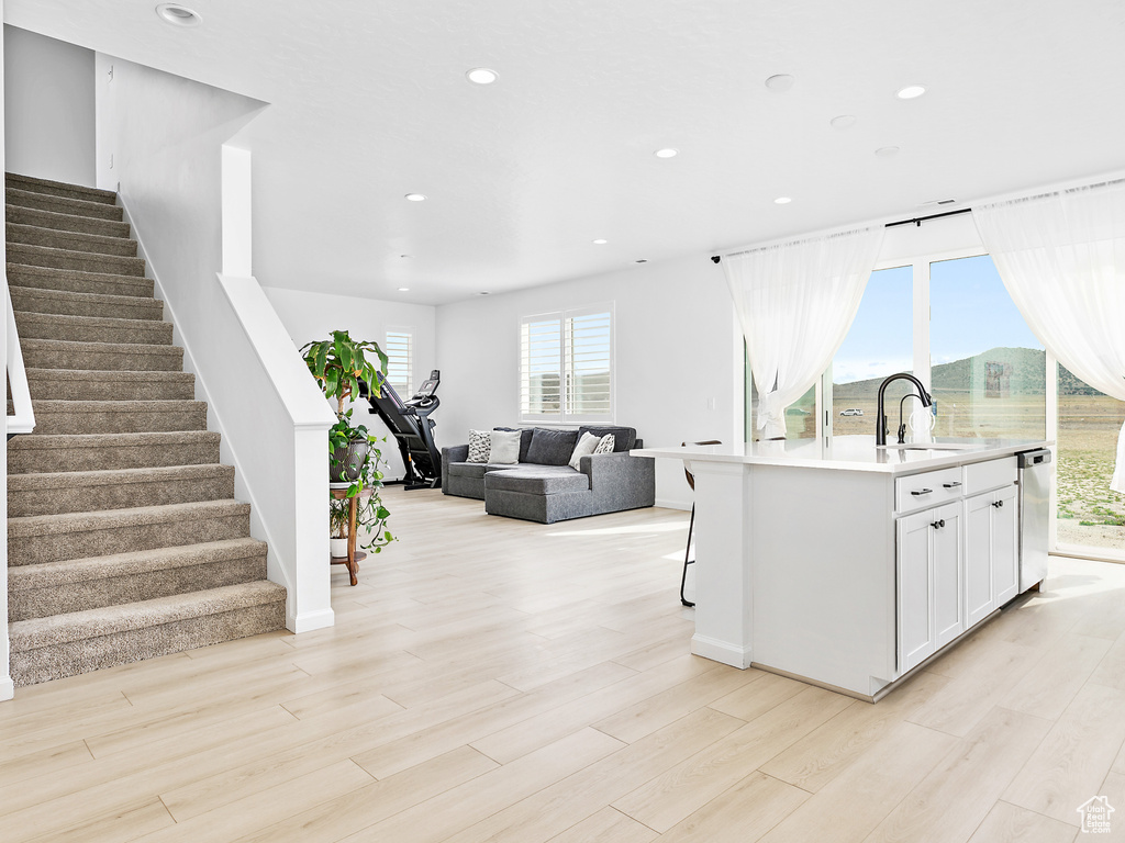 Kitchen with a sink, recessed lighting, white cabinetry, light wood-style flooring, and light countertops