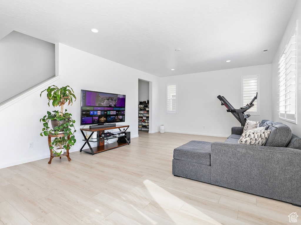 Living room with wood finished floors, recessed lighting, baseboards, and stairway
