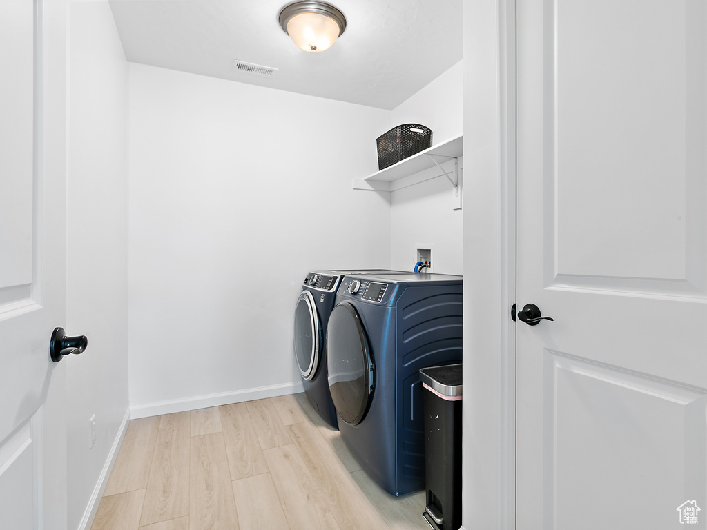 Laundry area featuring independent washer and dryer, light wood finished floors, and baseboards