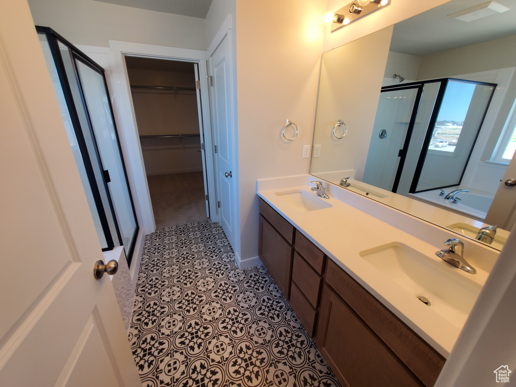 Full bathroom featuring a stall shower, double vanity, a walk in closet, and a bath